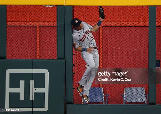 Mauricio Dubon of the Houston Astros collides with the outfield fence as he fails to catch this two-run double by Dansby Swanson of the Atlanta...