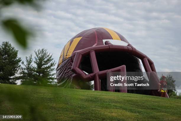 General view as a fan walks through the inflatable Washington Commanders helmet during training camp at INOVA Sports Performance Center on August 17,...