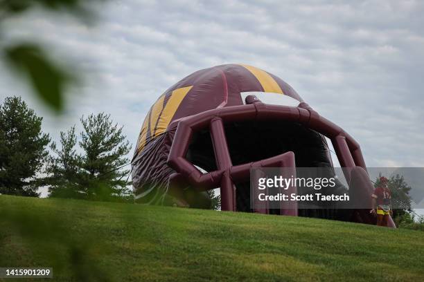 General view as a fan walks through the inflatable Washington Commanders helmet during training camp at INOVA Sports Performance Center on August 17,...