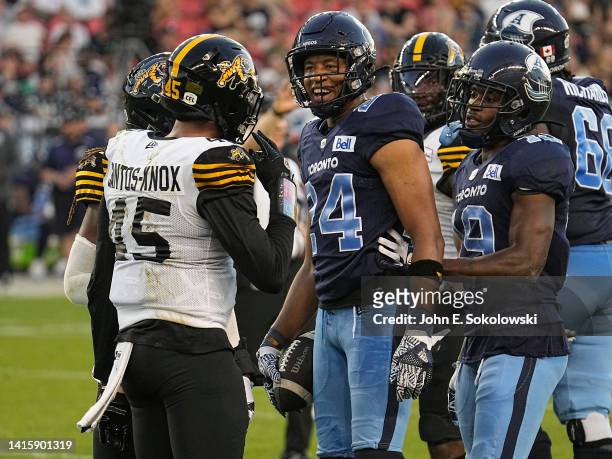 Eric Rogers and Kurleigh Gittens Jr. #19 of the Toronto Argonauts exchange words with Jovan Santos-Knox of the Hamilton Tiger-Cats after a play at...