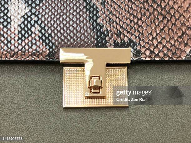 green lady's handbag with animal patterned flap showing gold metal lock - snakeskin stock pictures, royalty-free photos & images