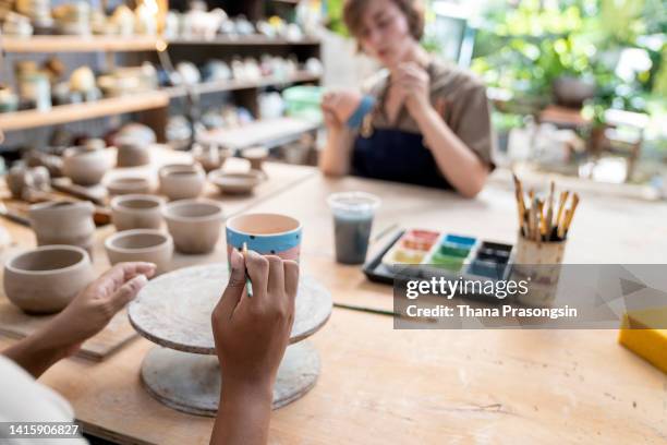 close-up of woman painting pottery - painting pottery stock pictures, royalty-free photos & images