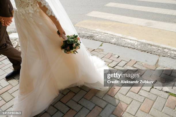 a young woman and a man walk along a pedestrian crossing. the feet of the newlyweds step on the white zebra stripe. the concept of safety, proper lifestyle, compliance with traffic rules. the wedding day. - wedding feet stock-fotos und bilder