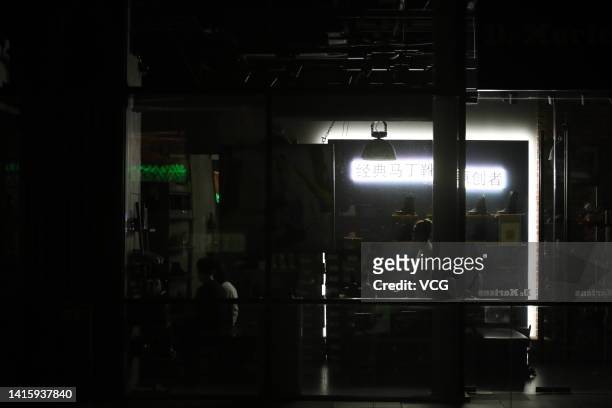 Shoppers are seen inside a shoe shop at the Taikoo Li shopping complex as many lights are switched off to conserve energy on August 19, 2022 in...