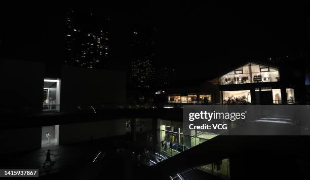 People walk in the darkness at the Taikoo Li shopping complex as many lights are switched off to conserve energy on August 19, 2022 in Chengdu,...