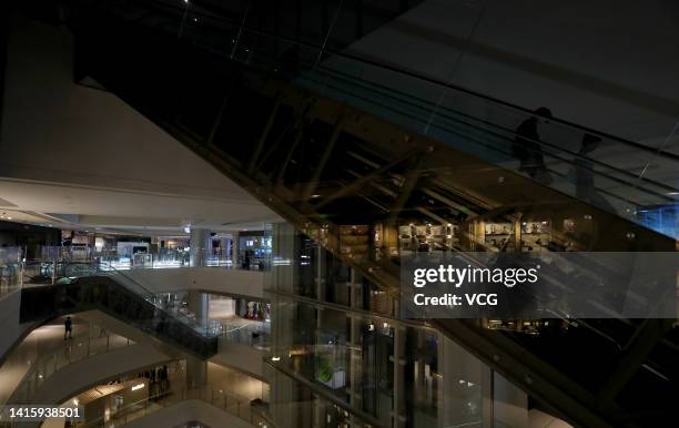 People walk inside a shopping mall at the Chunxi Road pedestrianized shopping street as many lights are switched off to conserve energy on August 19,...