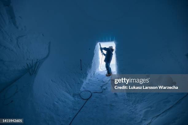 Sepp Kipfstuhl of the East Greenland Ice-Core Project works with a chainsaw to cut a larger entrance to the new tunnel at EastGRIP camp on August 6,...