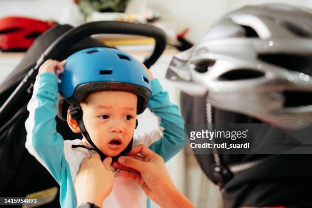 mother putting a helmet on her son's head - familie fietsen close up stockfoto's en -beelden