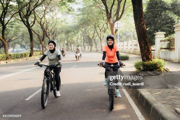 muslim woman riding bicycle - islamic action front stock pictures, royalty-free photos & images