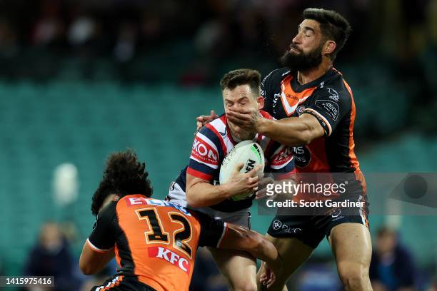 Joseph Suaalii of the Roosters is tackled by James Tamou and Daine Laurie of the Tigers during the round 23 NRL match between the Sydney Roosters and...