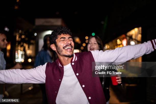 mid adult man singing with friends in the street at night - drunk guy stock pictures, royalty-free photos & images