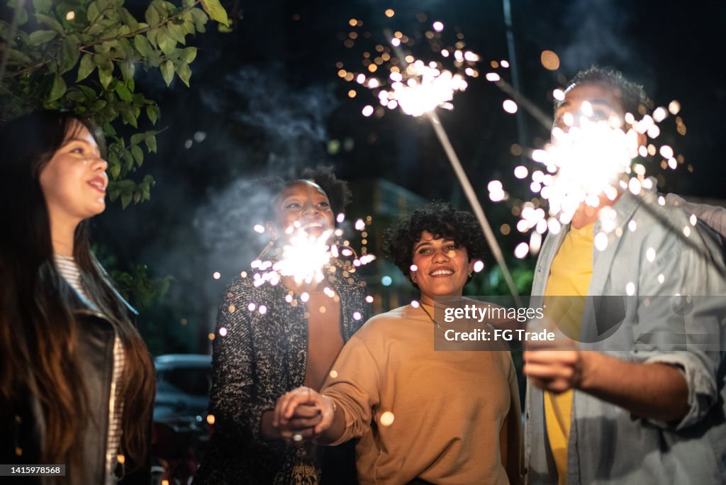Friends celebrating with sparkers in the street at night