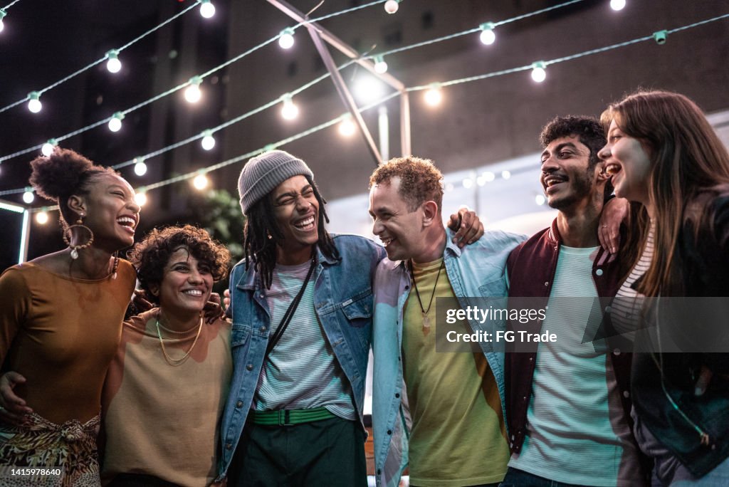 Friends embracing having fun in the street at night