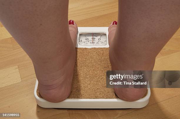 An anonymous woman on the scales before her weight loss surgery. The scales stop at 19 stone, but she weighs nearly 20 stone and is severely obese....