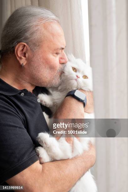 active senior man kissing his beautiful kitten - hairy old man stockfoto's en -beelden