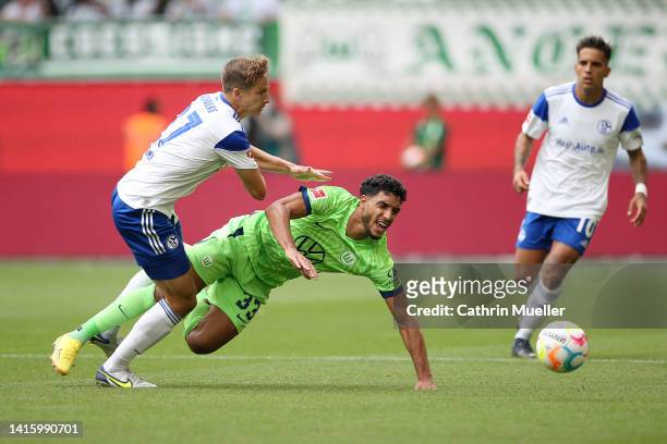 Omar Marmoush of VfL Wolfsburg is tackled by Cedric Brunner of FC Schalke 04 during the Bundesliga match between VfL Wolfsburg and FC Schalke 04 at...
