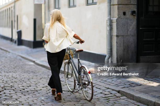 Guest wears a pale yellow short sleeves shirt, black large pants, brown and black leopard print pattern suede / high block heels sandals , outside...