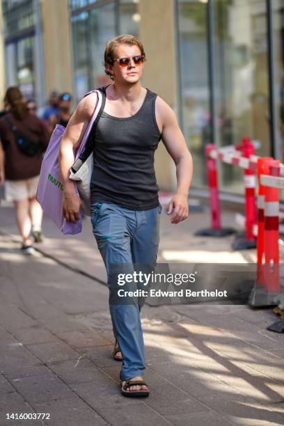 Guest wears sunglasses, a dark gray tank-top, a pale purple with green inscriptions print pattern cotton shoulder bag, blue gray large pants, velcro...