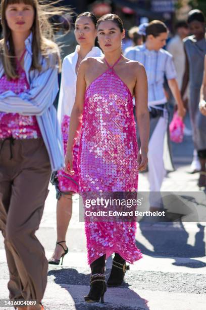 Guest wears a neon pink embroidered sequined / halter-neck / long dress, black suede pointed / heels knees boots with silver and gold ankle chains,...