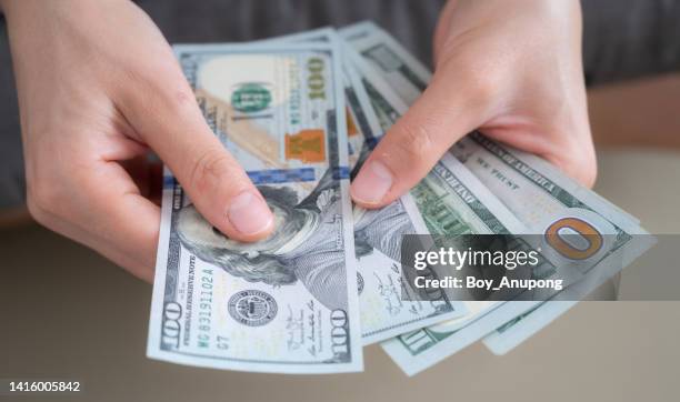 close up of someone hands holding and counting american dollar banknotes in her hand. - banknote stock-fotos und bilder