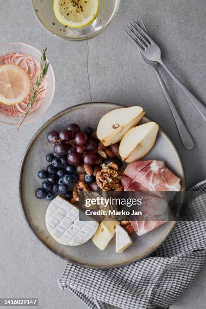 cheese plate with prosciutto, pears, nuts and grapes - ham salami stockfoto's en -beelden