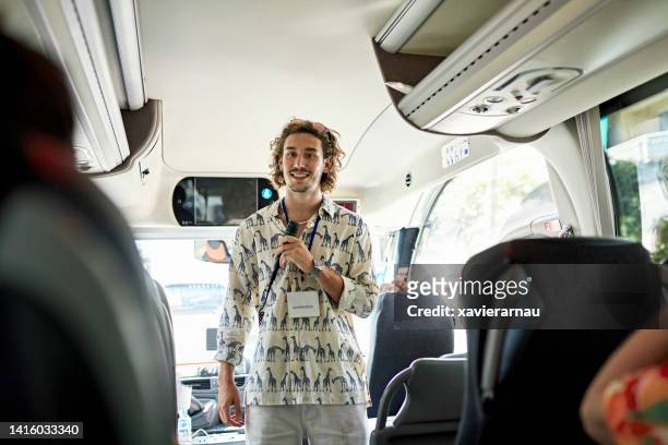 ehrliches porträt eines jungen busfahrers mit mikrofon - reiseführer stock-fotos und bilder