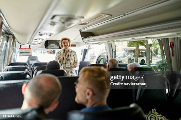 smiling tour guide with microphone on coach bus - gids stockfoto's en -beelden