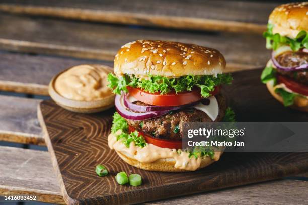 hamburguesa con queso en una tabla de cortar de madera casera con un fondo oscuro - hamburguesa vegetariana fotografías e imágenes de stock