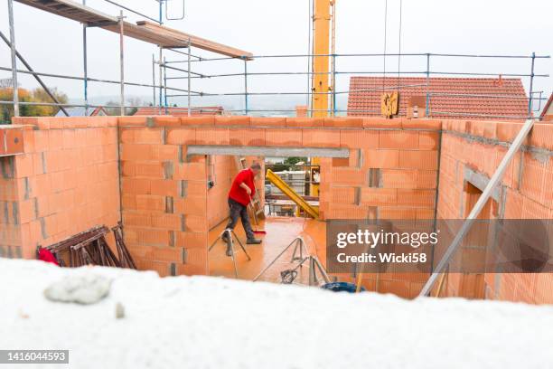 construction workers in bad weather on a construction site - latei stockfoto's en -beelden