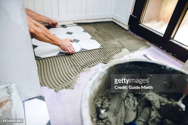 man flooring with tiles at home doing diy renovation project. - rebuilding fotografías e imágenes de stock