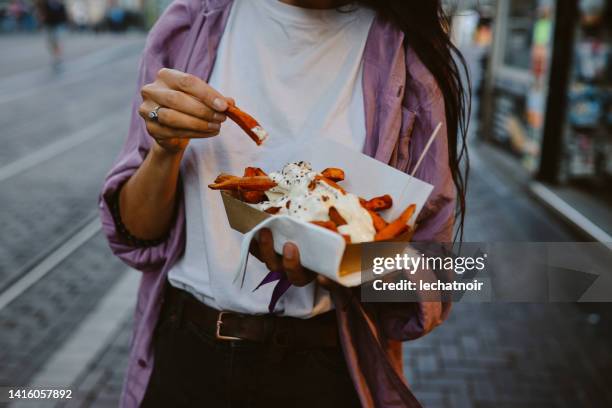 sweet potato fries in amsterdam - woman junk food eating stockfoto's en -beelden