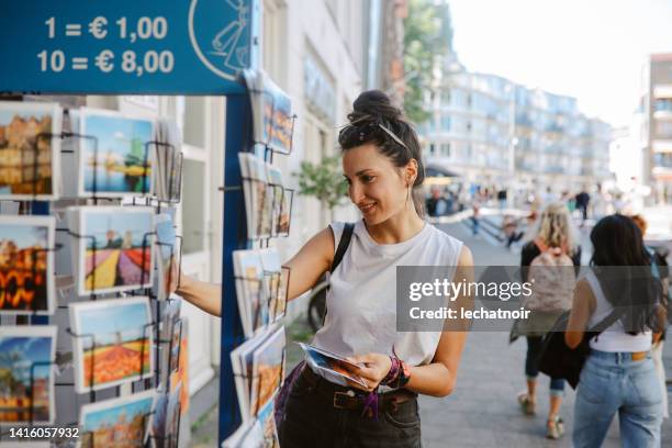 tourist buying postcards in amsterdam - souvenir stockfoto's en -beelden
