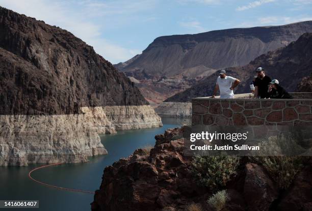 Park visitors look at a bleached 'bathtub ring' that is visible on the banks of Lake Mead near the Hoover Dam on August 19, 2022 in Lake Mead...