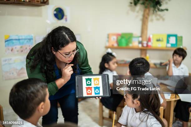 teacher talking to students about recycling in the classroom at school - woman uniform stock pictures, royalty-free photos & images