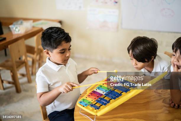 boy playing musical instrument in the classroom - xylophone stock pictures, royalty-free photos & images