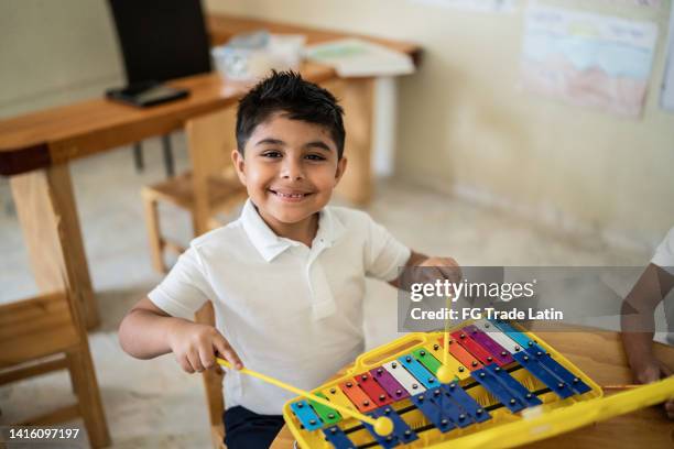 portrait of boy playing musical instrument in the classroom - xylophone stock pictures, royalty-free photos & images