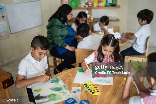 estudiantes pintando en el aula de la escuela - niña en edad escolar fotografías e imágenes de stock