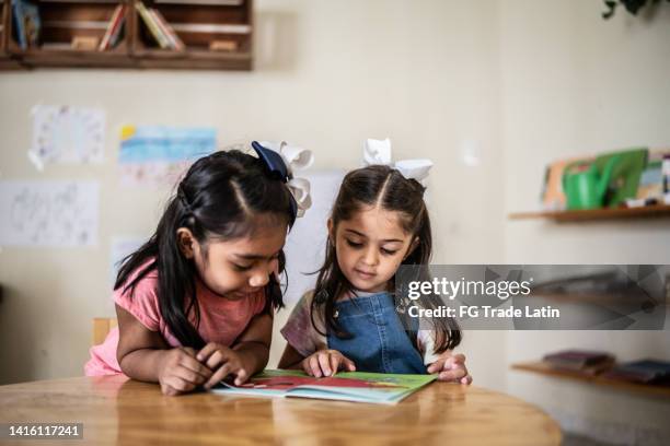 girls reading book in classroom at school - children reading stock pictures, royalty-free photos & images