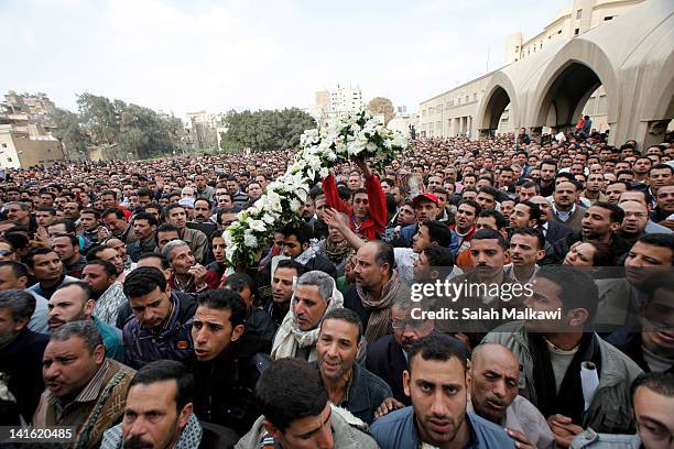 Flowers are held above the crowd as Egyptian Christians mourn at the funeral of Pope Shenouda III, the head of Egypt's Coptic Orthodox Church, near...