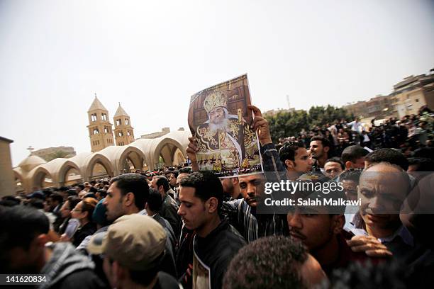 Poster is held aloft as Egyptian Christians mourn at the funeral of Pope Shenouda III, the head of Egypt's Coptic Orthodox Church, in the Abassiya...