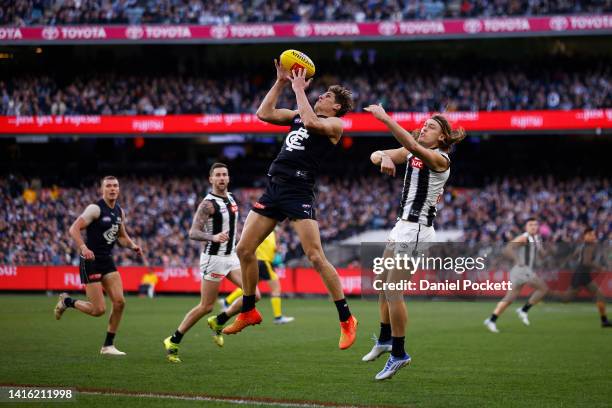 Charlie Curnow of the Blues marks the ball against Darcy Moore of the Magpies during the round 23 AFL match between the Carlton Blues and the...