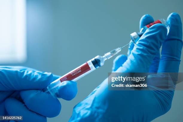 close up  doctor hand suing syringe vaccination anti virus  monkeypox new strain with vial vaccine and blood test tube - anti vaccine stock-fotos und bilder