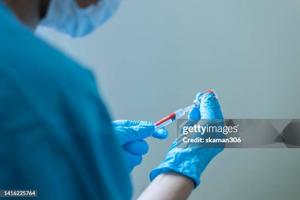 close up doctor hand suing syringe vaccination anti virus monkeypox new strain with vial vaccine and blood test tube - epidemic stock pictures, royalty-free photos & images