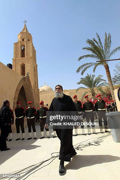 An Egyptian Coptic priest walks in front of military police at the Bishoy Monastery during the funeral of Pope Shenuda III, the spiritual leader of...
