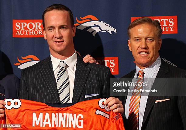 Quarterback Peyton Manning poses executive vice president of football operations John Elway during a news conference announcing Manning's contract...