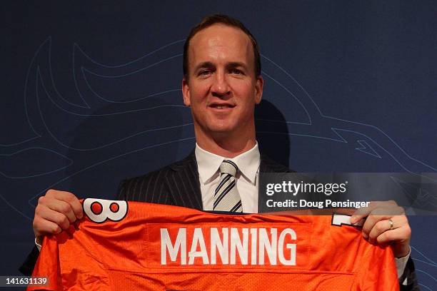 Quarterback Peyton Manning poses with his uniform after the news conference announcing his contract with the Denver Broncos in the team meeting room...