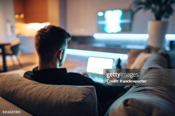 man working on the couch and watching tv - student behind laptop stock pictures, royalty-free photos & images