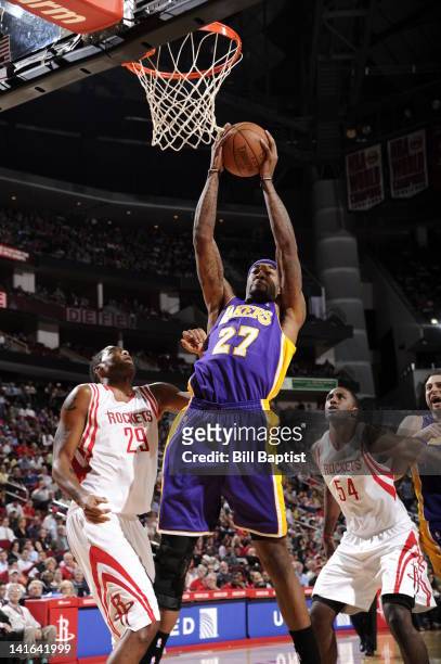 Jordan Hill of the Los Angeles Lakers goes to the basket against Marcus Camby and Patrick Patterson of the Houston Rockets during the game between...