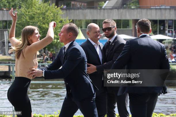 Member of the topless feminist action group Femen throws fake bloody 50 euro notes at German Chancellor Olaf Scholz as she is arrested while...