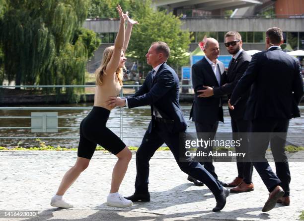 Member of the topless feminist action group Femen throws fake bloody 50 euro notes at German Chancellor Olaf Scholz as she is arrested while...